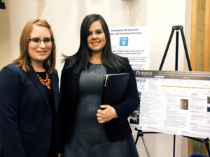 Two young woman in front of their poster