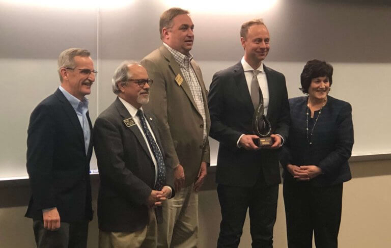 Jacob holding award with a group of adults smiling to the camera