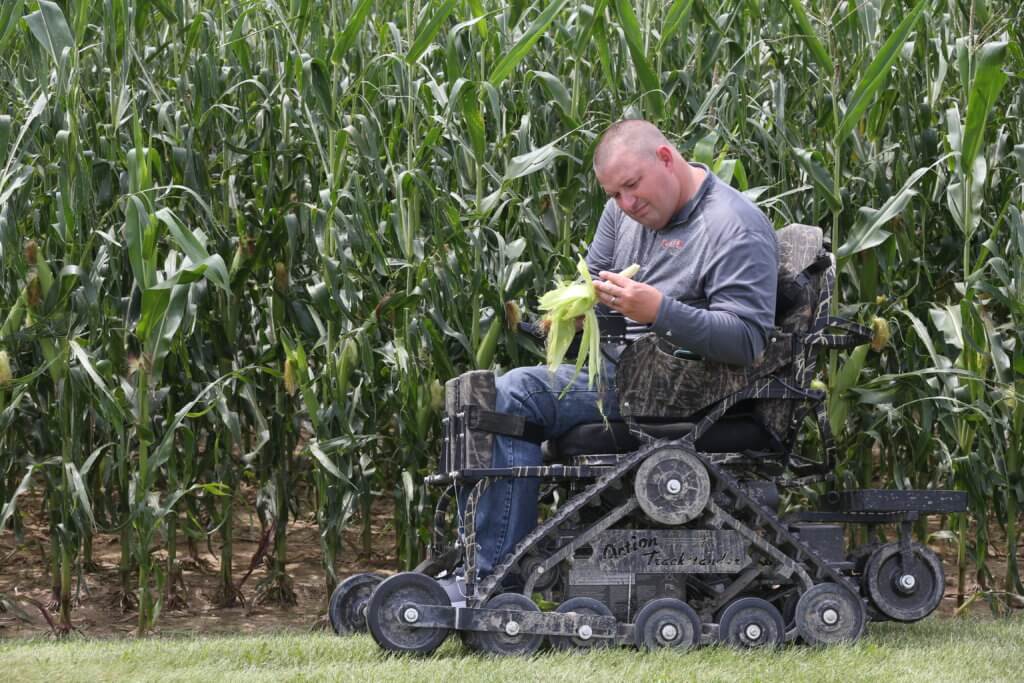 man in wheelchair outside in a cornfield