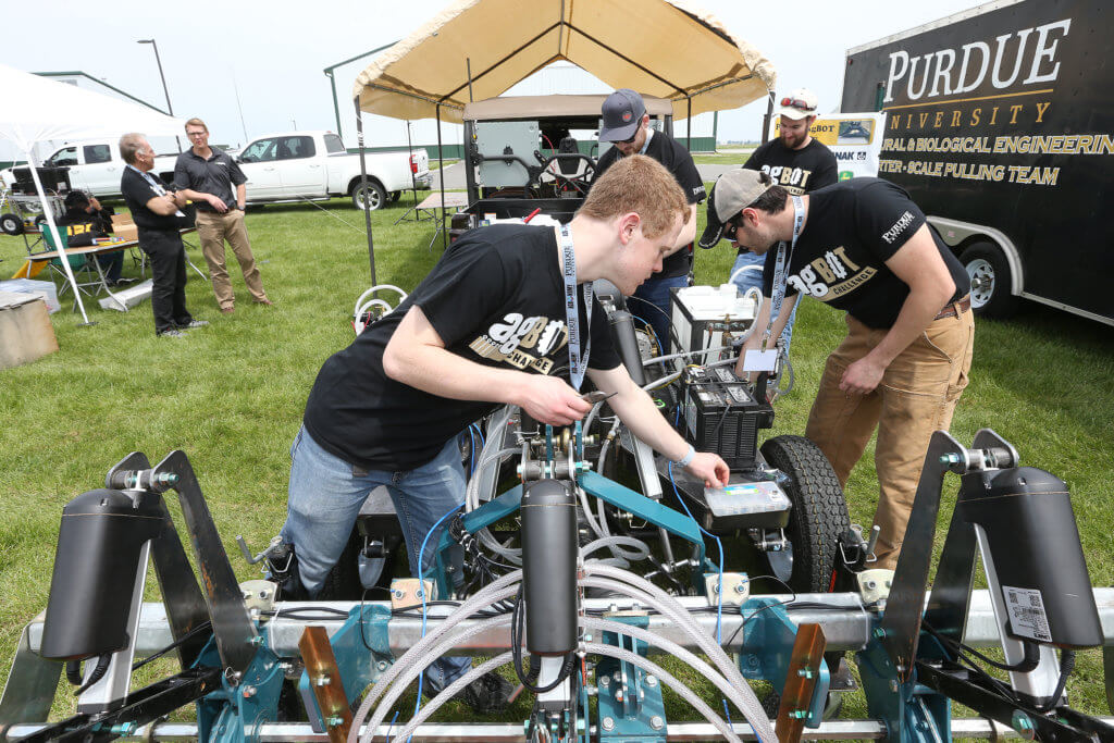 students making adjustments to a small car