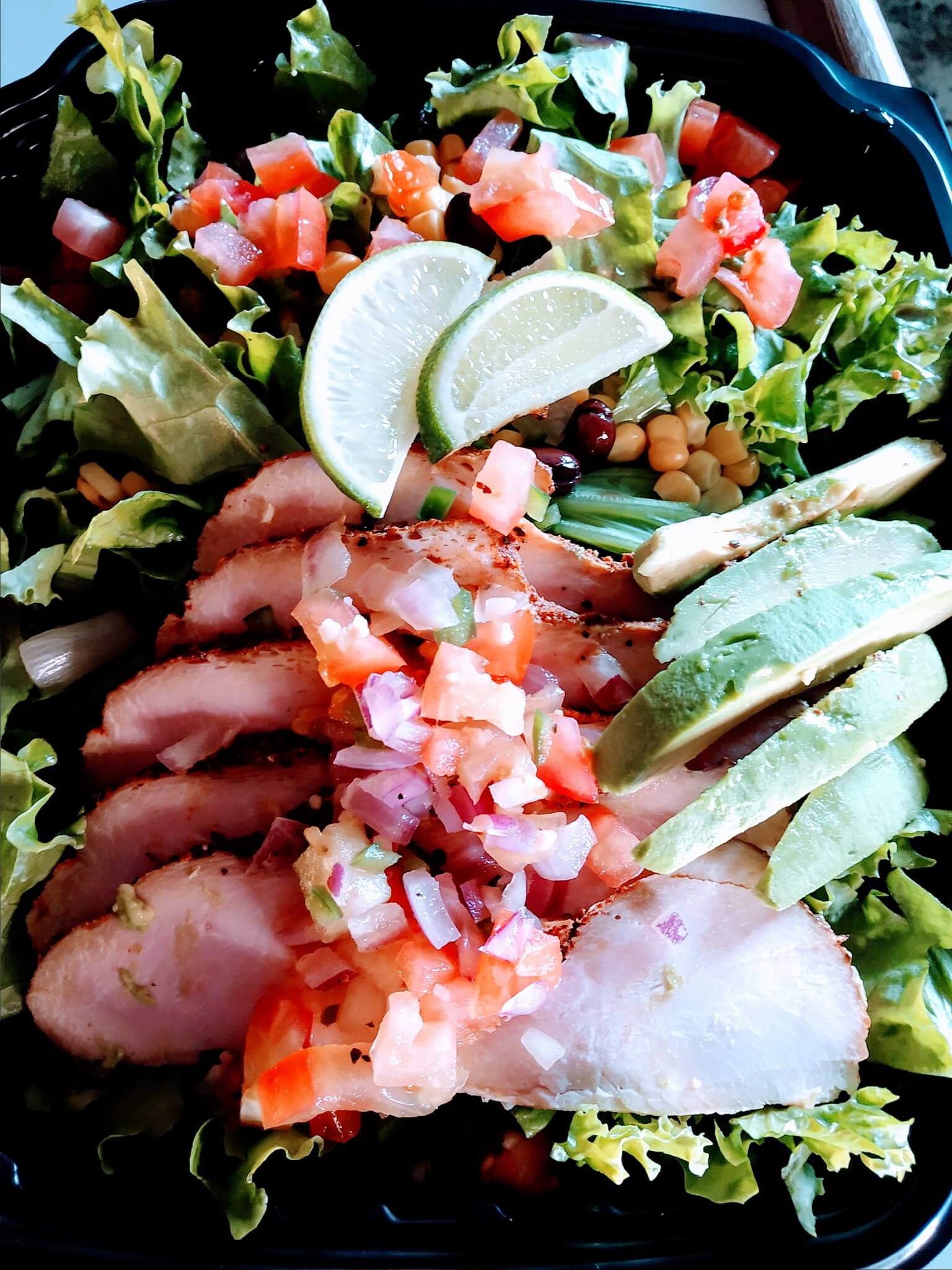 Dinner plate displaying an arrange of slices of ham surrounded with vegetables 