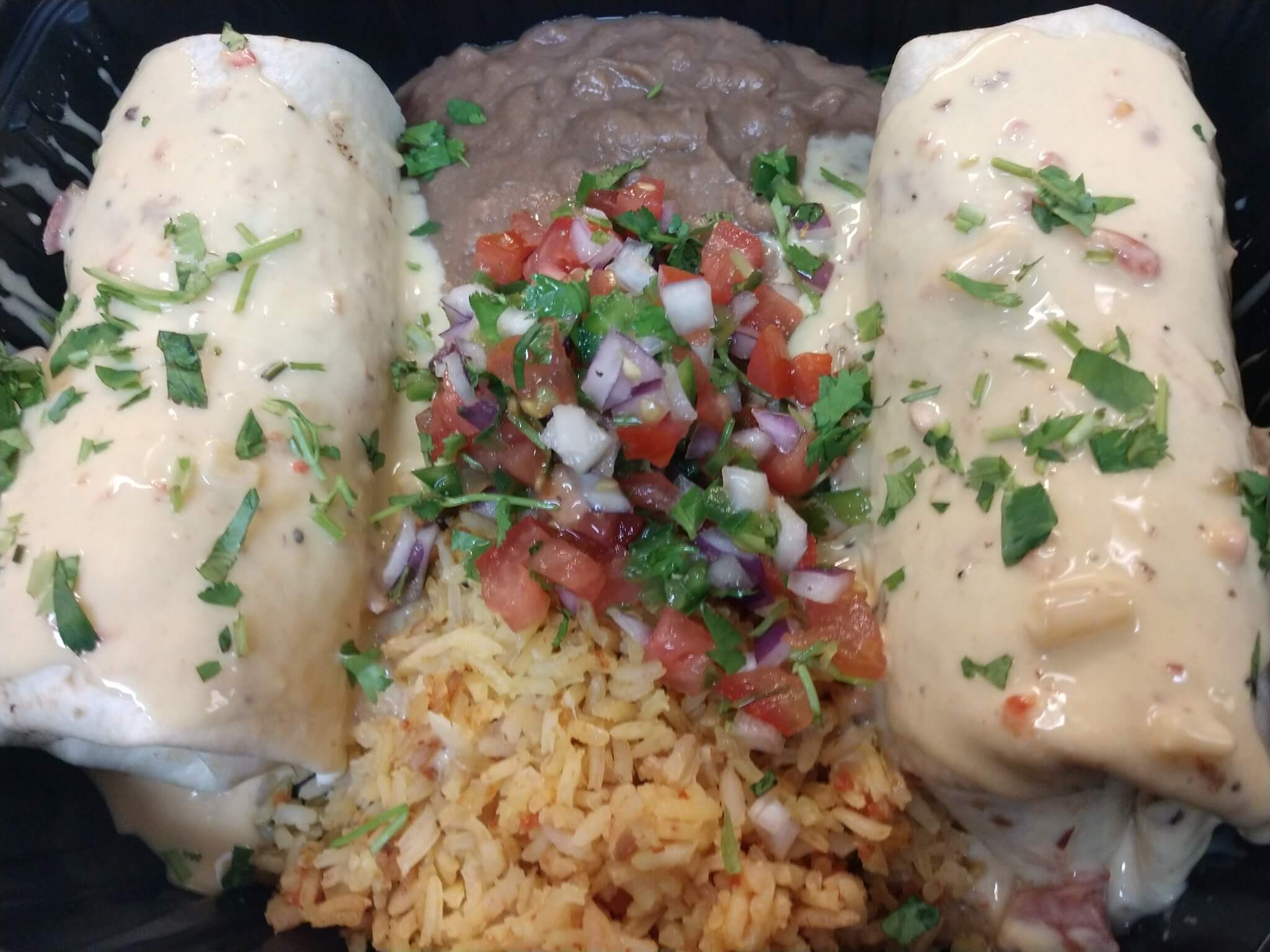 Specialty burrito box (two burritos with rice and in the middle top with chop tomatoes, onion and cilantro)