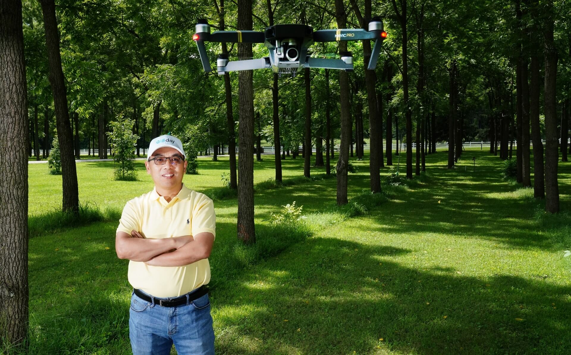 Professor Fei in a tree plantation and a drone suspended on the air