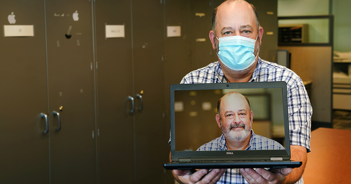 Richard Fox hoging a laptop with his portrait on it