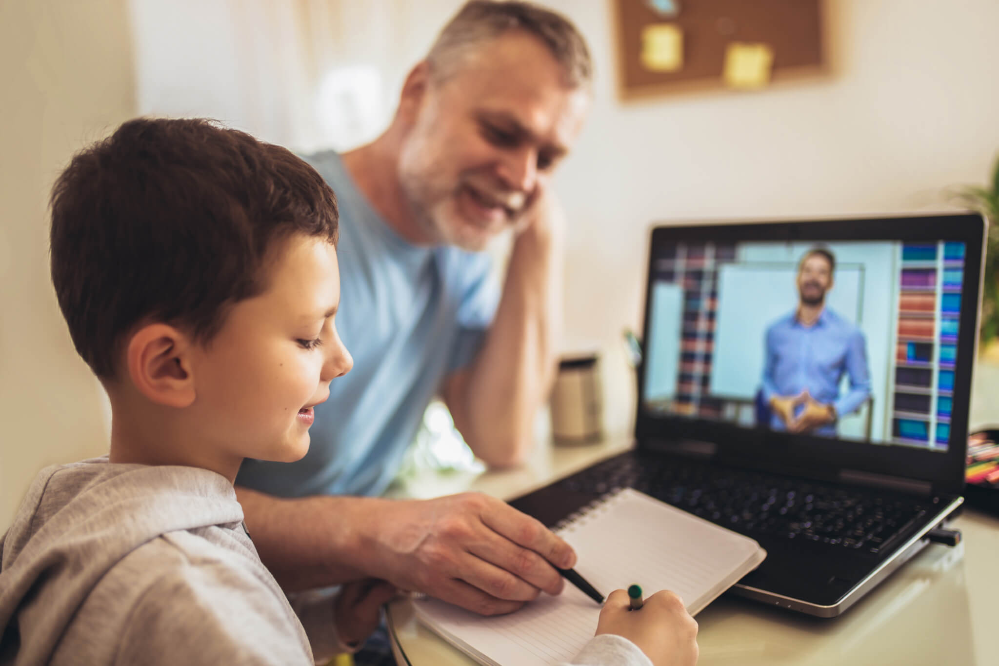 father with young kid following online school modality