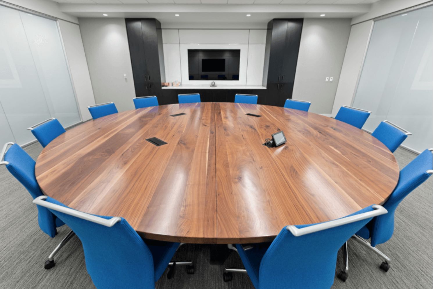Modern office with big round wooden table with blue office chairs