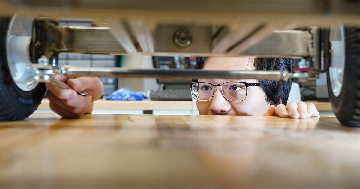 Agricultural & Biological Engineering, grad student makes a tabletop tie rod adjustment on a small robotic kart