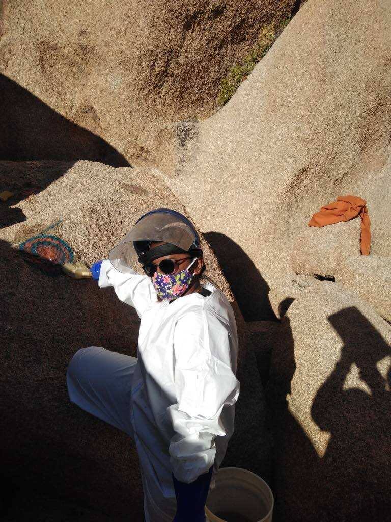 Bera working cleaning graffiti off rocks