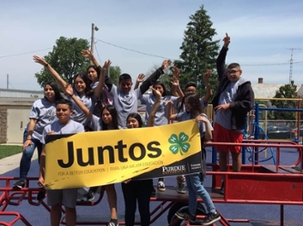 A group of kids, members of juntos, holding a banner cheering proudly 