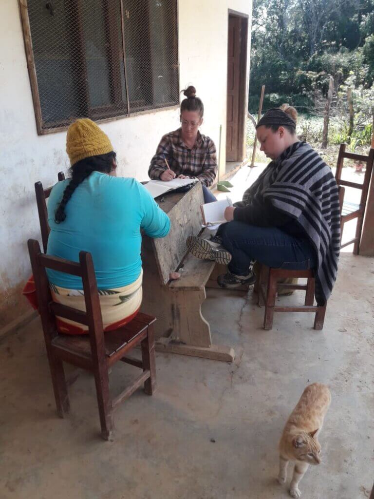 BROOKE MCWHERTER outside a small cabin writing her research with locals in the mountains of Bolivia 