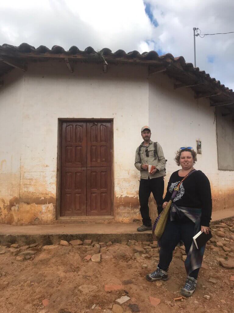 BROOKE MCWHERTER outside a small cabin with locals in the mountains of Bolivia 
