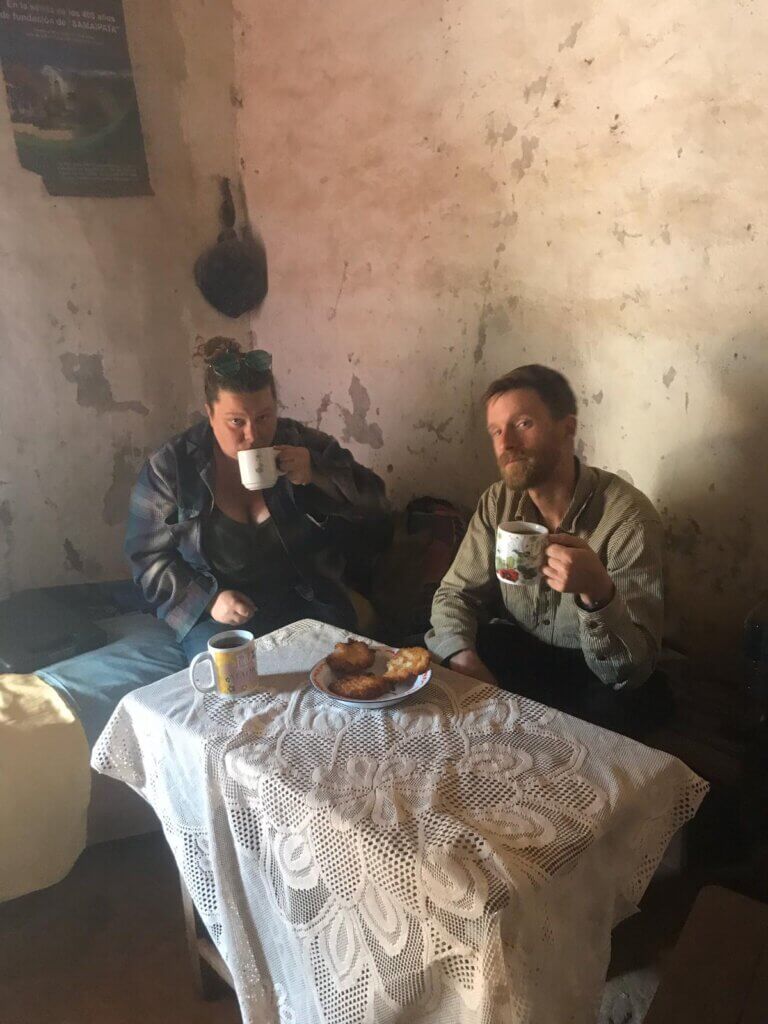 BROOKE MCWHERTER drinking coffee inside a small cabin with locals in the mountains of Bolivia 