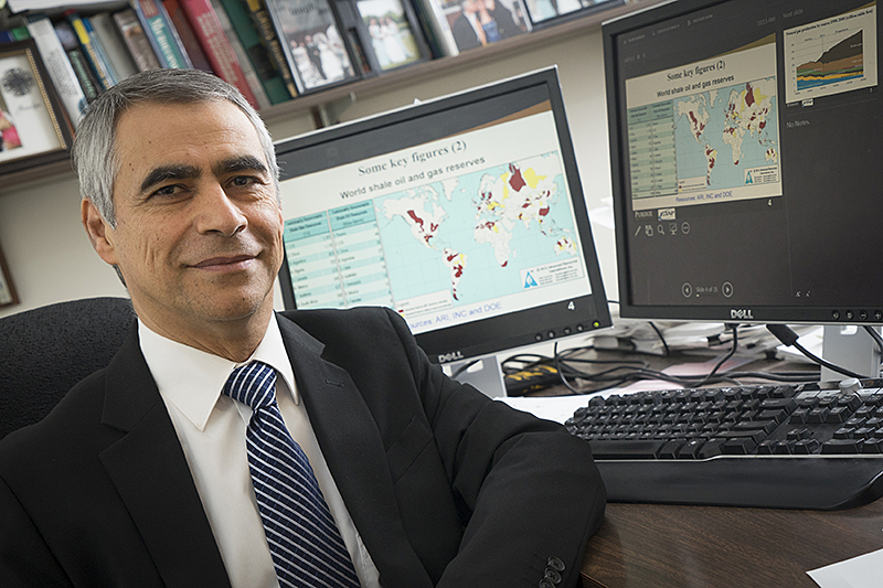 Farzad Taheripour in a suit, graphics in computer monitors in the back