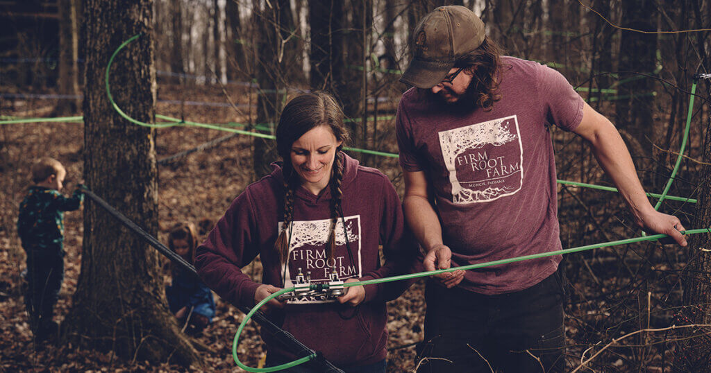 Young couple working on maple syrup tubing that collects sap water