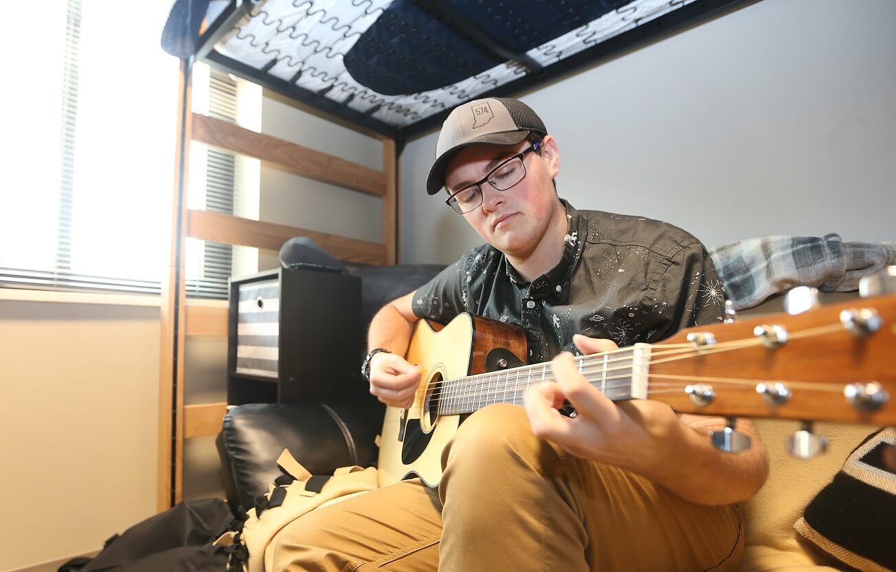 Picture of young man playing the guitar in his room