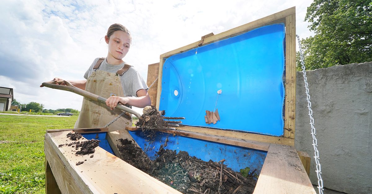 Sophia Mears, a junior majoring in horticulture, churns the composting barrel at the Purdue Student Farm.