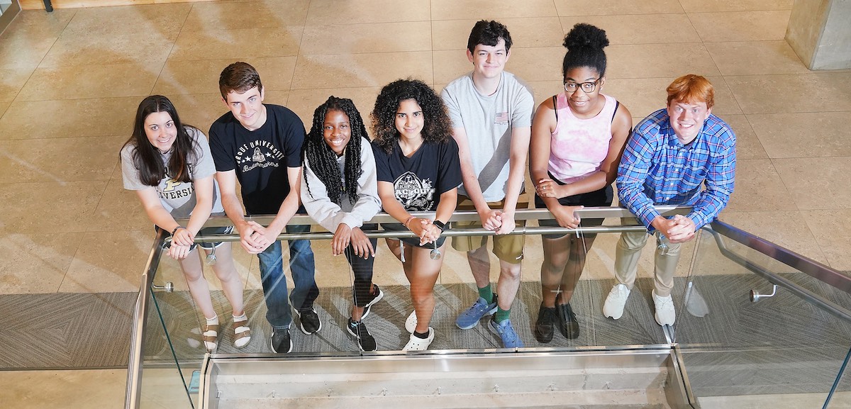 REEU 2022 program students stand along a railing inside the Agricultural and Biological Engineering Building.