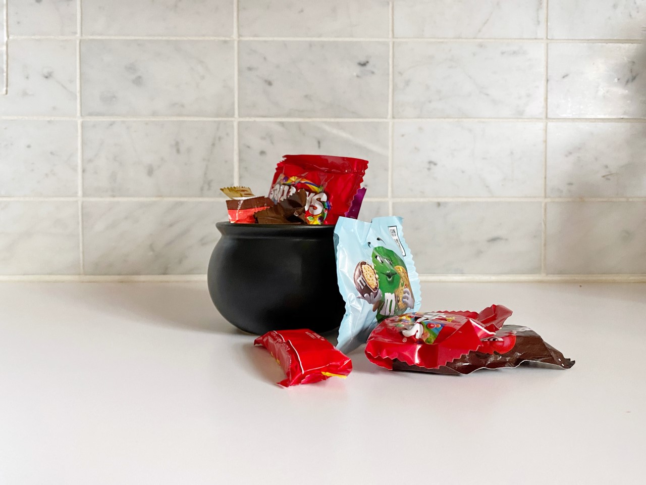 A cauldron filled with candy sits on a counter top.