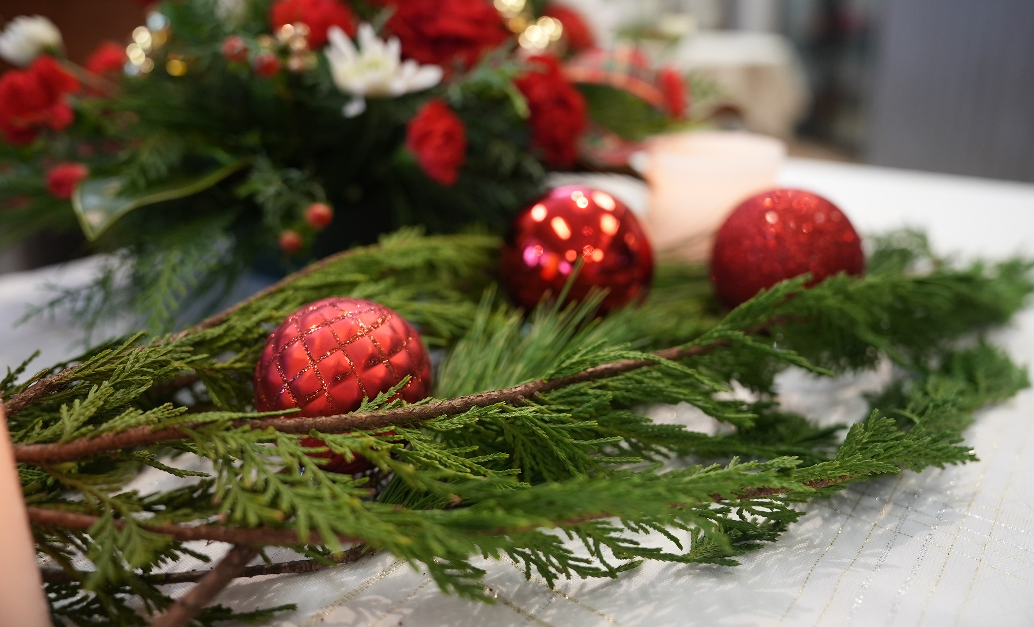 Greenery and red Christmas ornaments create a decorative centerpiece.