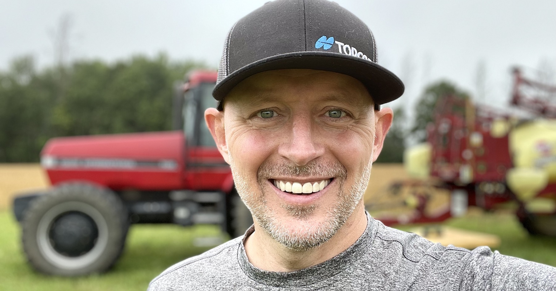 Dan Hendricks standing in front of a red tractor. 