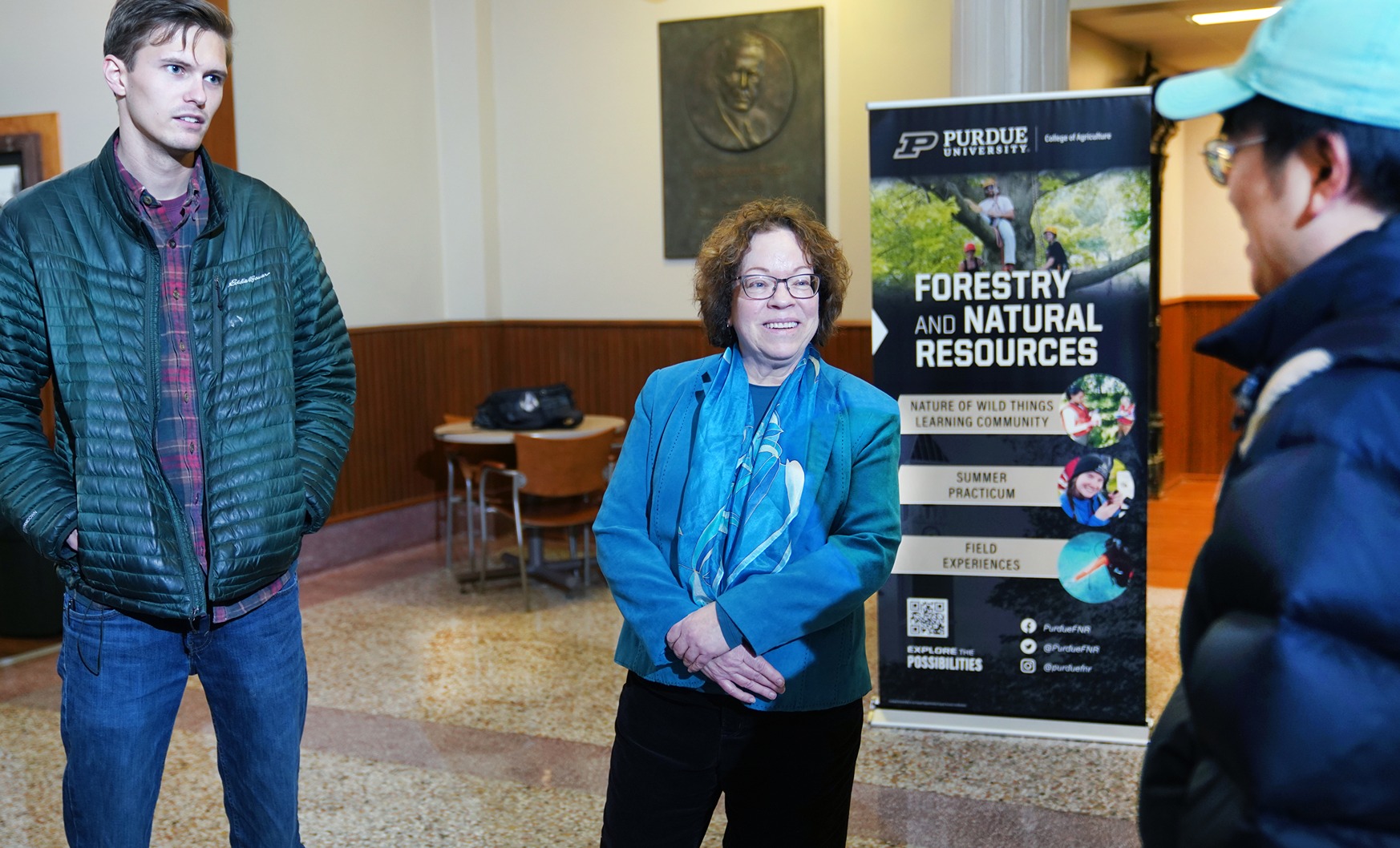 Jessica Gurevtich stands in Pfendler Hall to talk with a pair of forestry students.