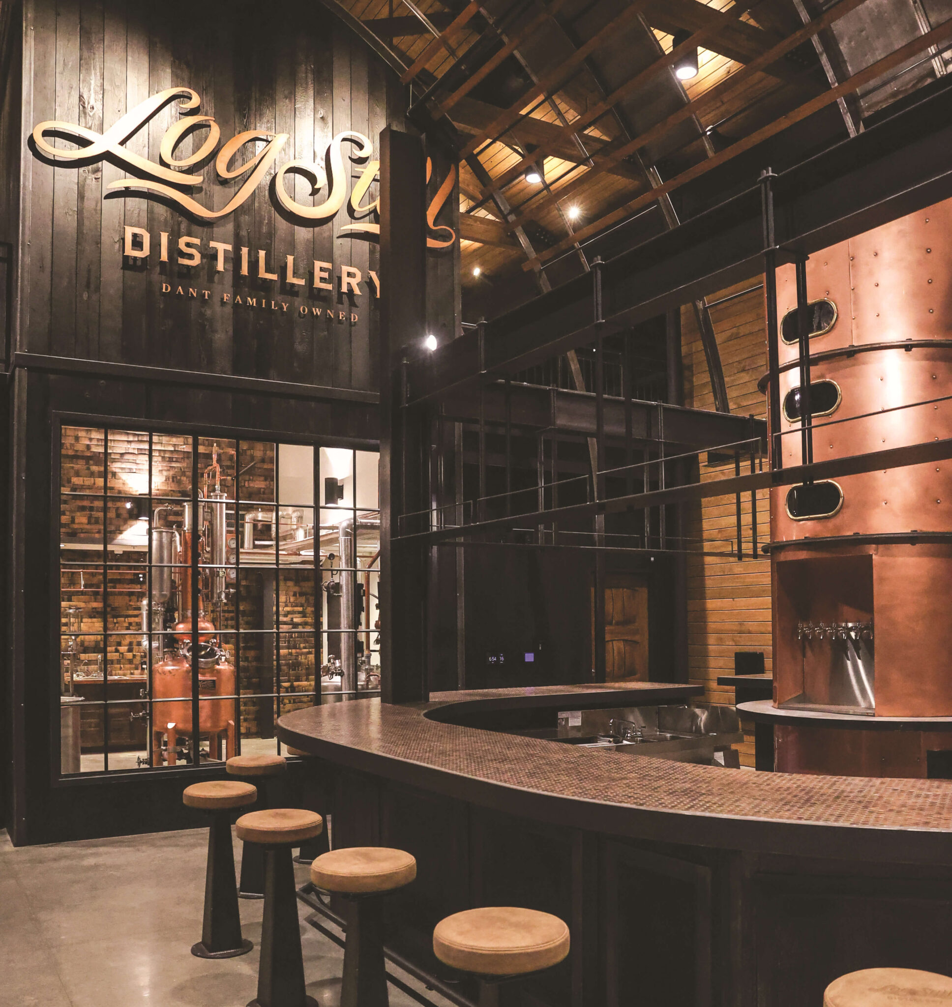 Dark and moody bourbon tasting room with bar and stools.