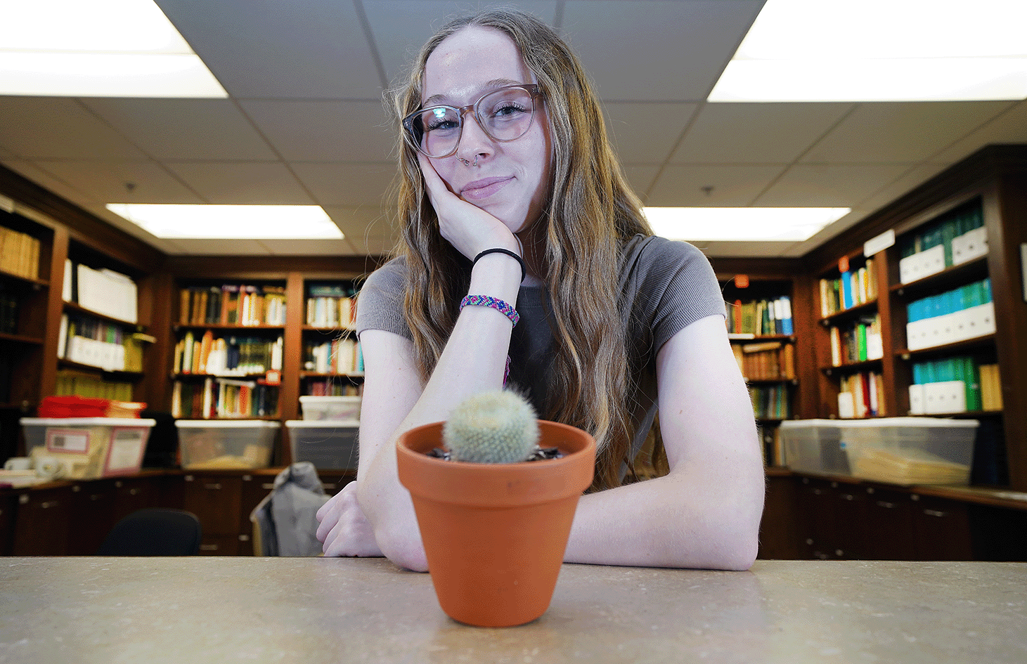 Sidney Bunch poses with the plant that got her started in studying botany, Mr. Cactus, in the library of the Purdue University Herbaria in Lily Hall