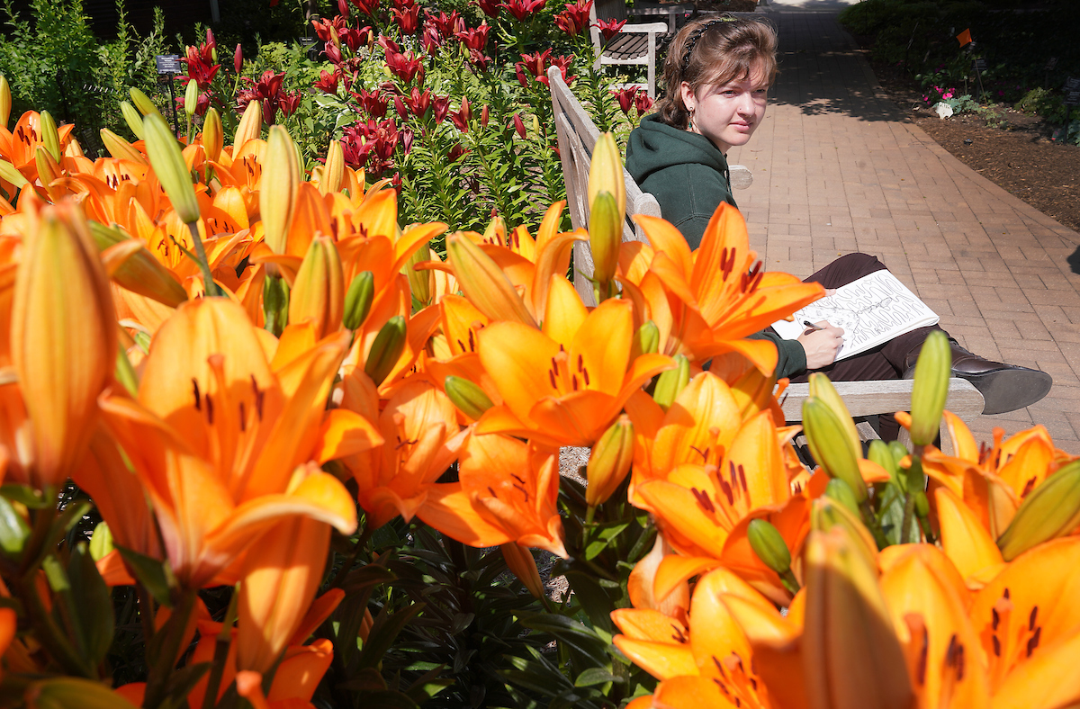 Levi Berry sketches out on a bench in the Jules Janick Garden