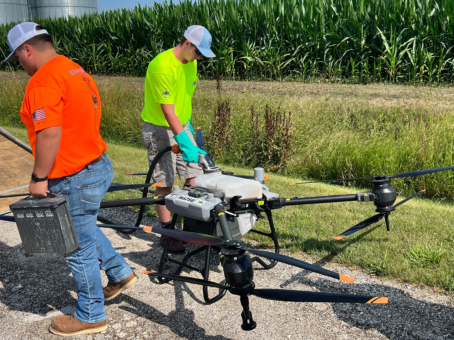 Tyler Ziehm, in a florescent yellow shirt, pumps the precise mixture of chemicals into the drone between the drone's flights