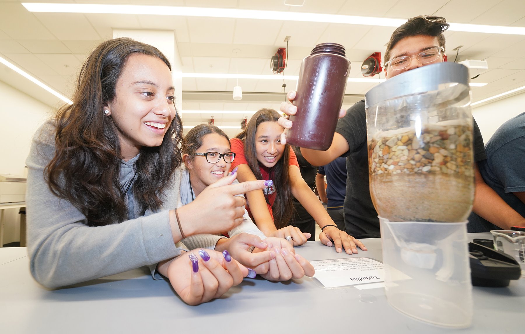 Participants in the Cargill-Purdue Agricultural Science Academy learning about water turbidity and ground water filtration using a plastic bottle, tap water and layers of gravel.Participants in the Cargill-Purdue Agricultural Science Academy learning about water turbidity and ground water filtration using a plastic bottle, tap water and layers of gravel.