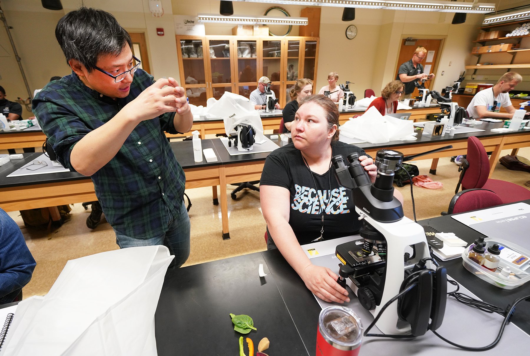 Purdue University professor of botany and plant pathology, Yun Zhou (left) answers questions in a lab for high school teachers and professionals. This session was one of many, during the 3 day C-PASA Professional Workshop, to help participants take back teaching tools to their programs. 