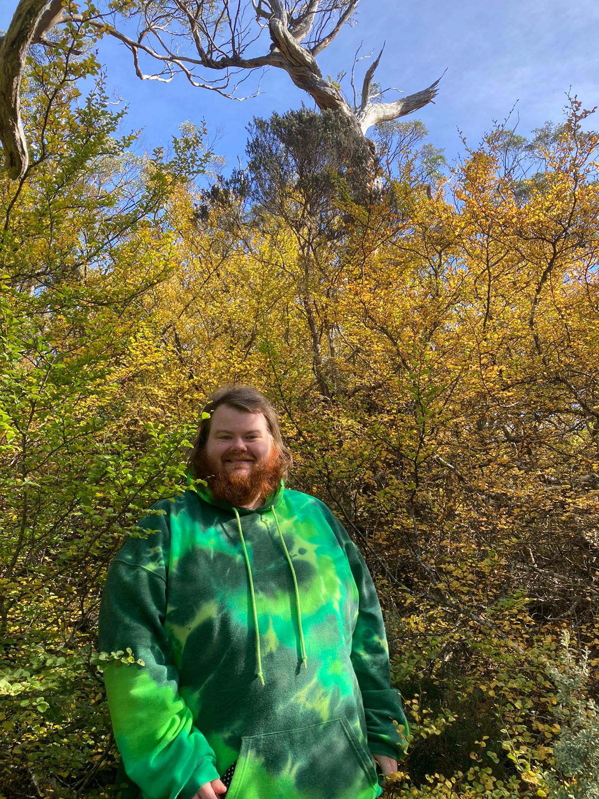 Cade Kane stands in front of some yellow bushes.