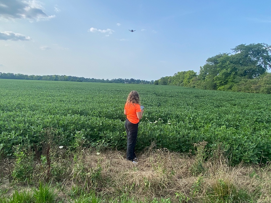 Chloe Hall in a field flying a drone.