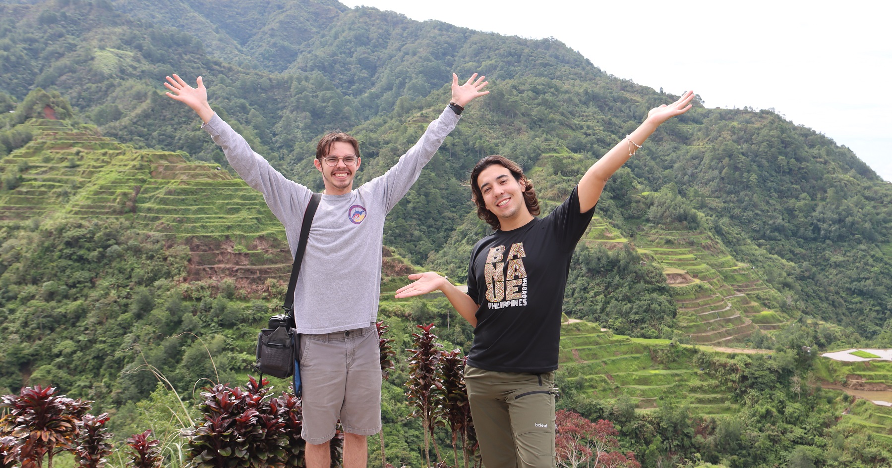 Student Matthew Haan stands with another person in front of mountains in the Philippines