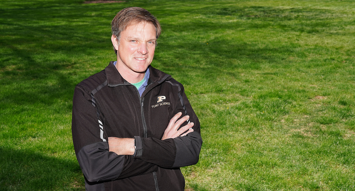 Cale Bigelow stands in front of a healthy lawn.