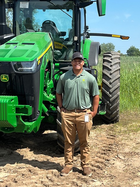 Parker stands in front of a John Deere Tractor