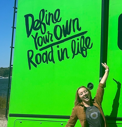 Maddie Milharcic stands in front of Road Trip Nation RV 