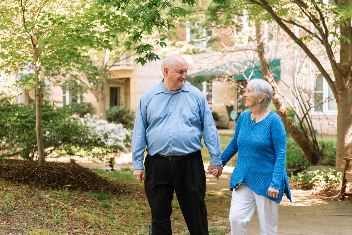 Bob and Karen Thompson walking side-by-side while smiling at each other and holding hands