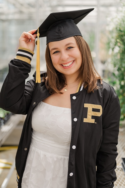 Student in cap and gown in greenhouse at Purdue