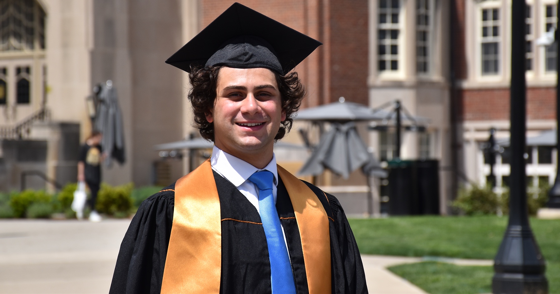 Remi Carrella stands in cap and gown at Purdue University in front of the union