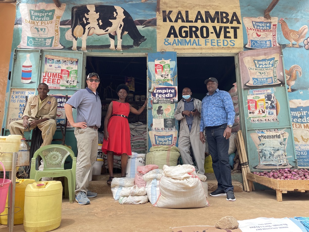 Jacob Ricker-Gilbert stands at the doorway entrance of a blue Kalamba Agro-Vet & Animal Feeds storefront