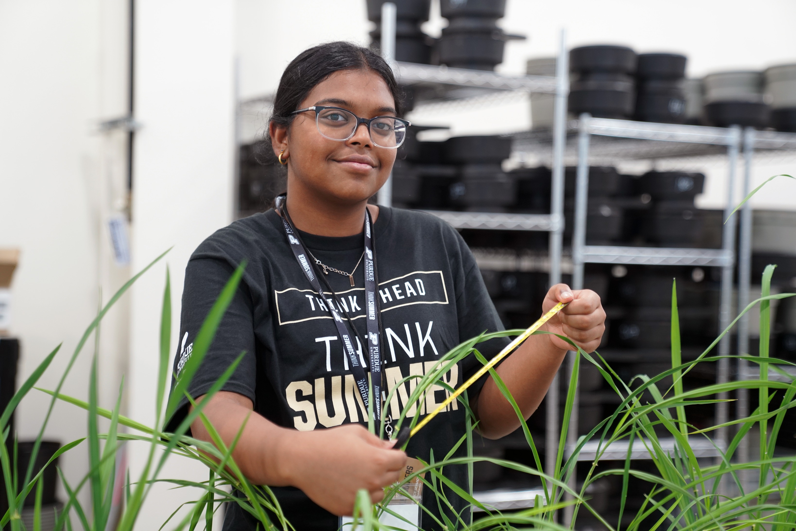 A high school student smiles and poses in the Ag Alumni Seed Phenotyping Facility.
