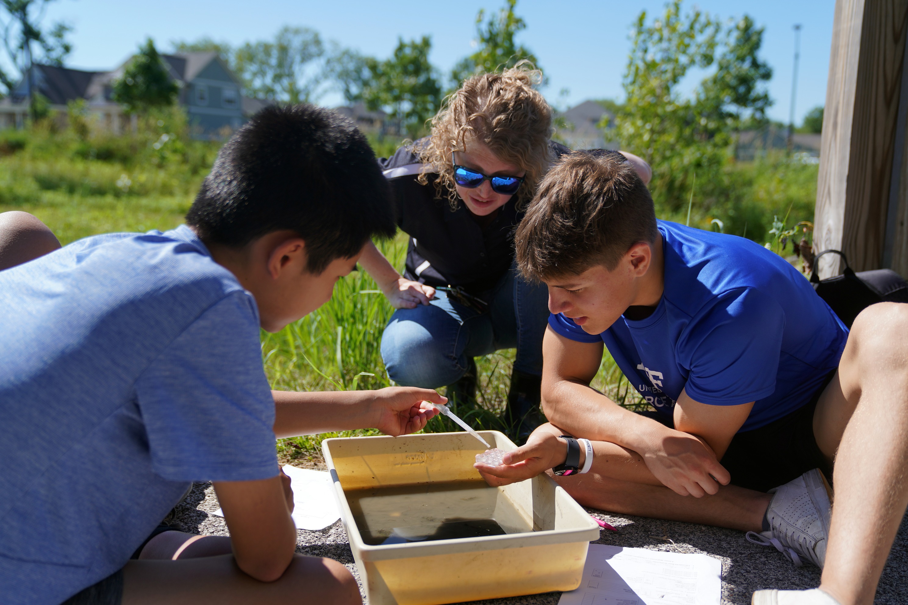 Caitlin Proctor observes creek water samples with students.