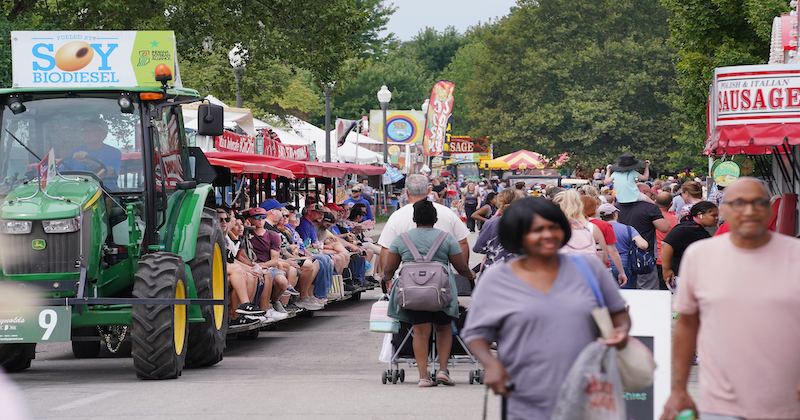 Fairgoers ride a tractor, sponsored by the Indiana Soybean Alliance, and browse food tents during the 2023 Indiana State Fair. (Purdue Agricultural Communications photo)