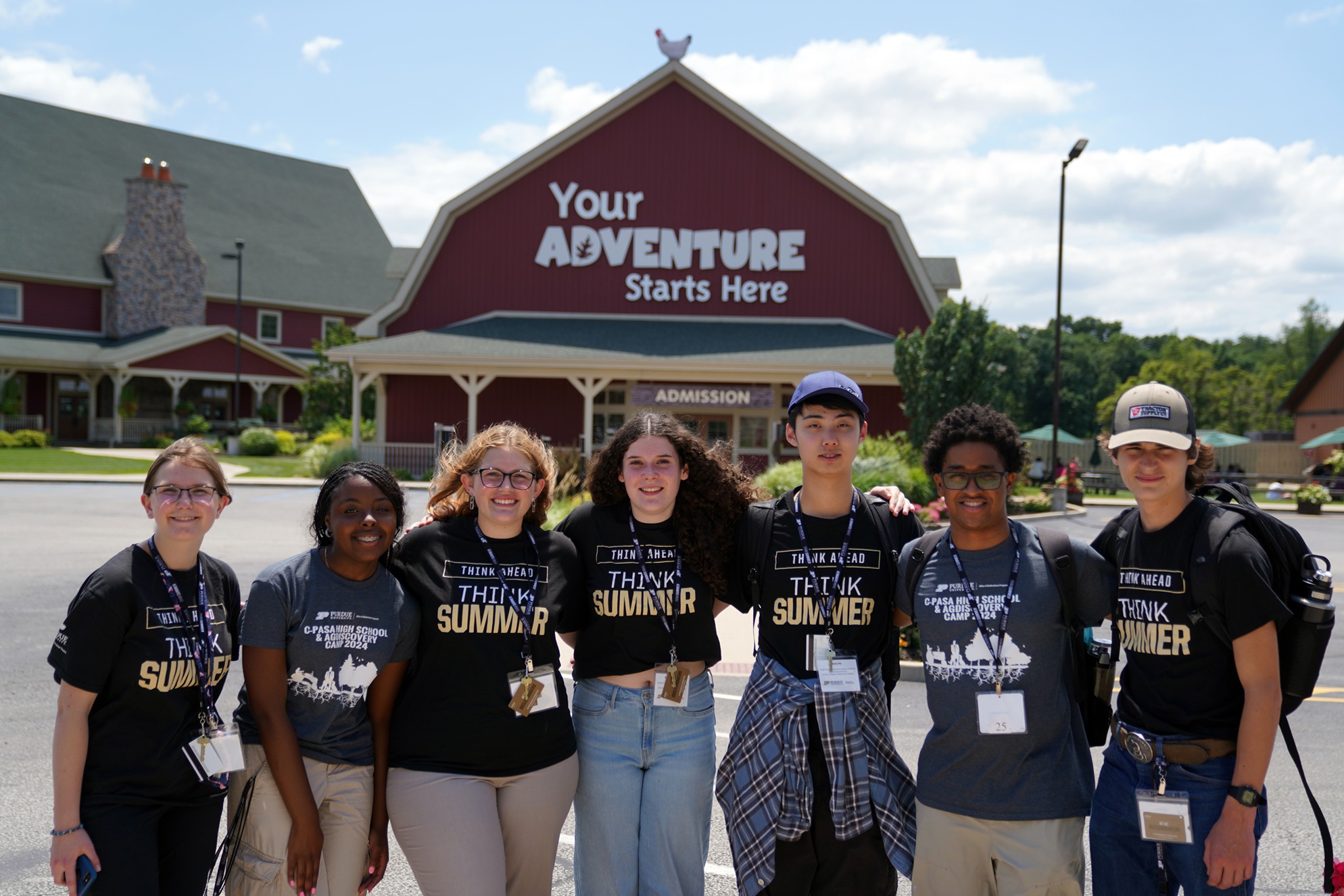 Students standing side-by-side at the entrance of Fair Oaks Farms' red barn.