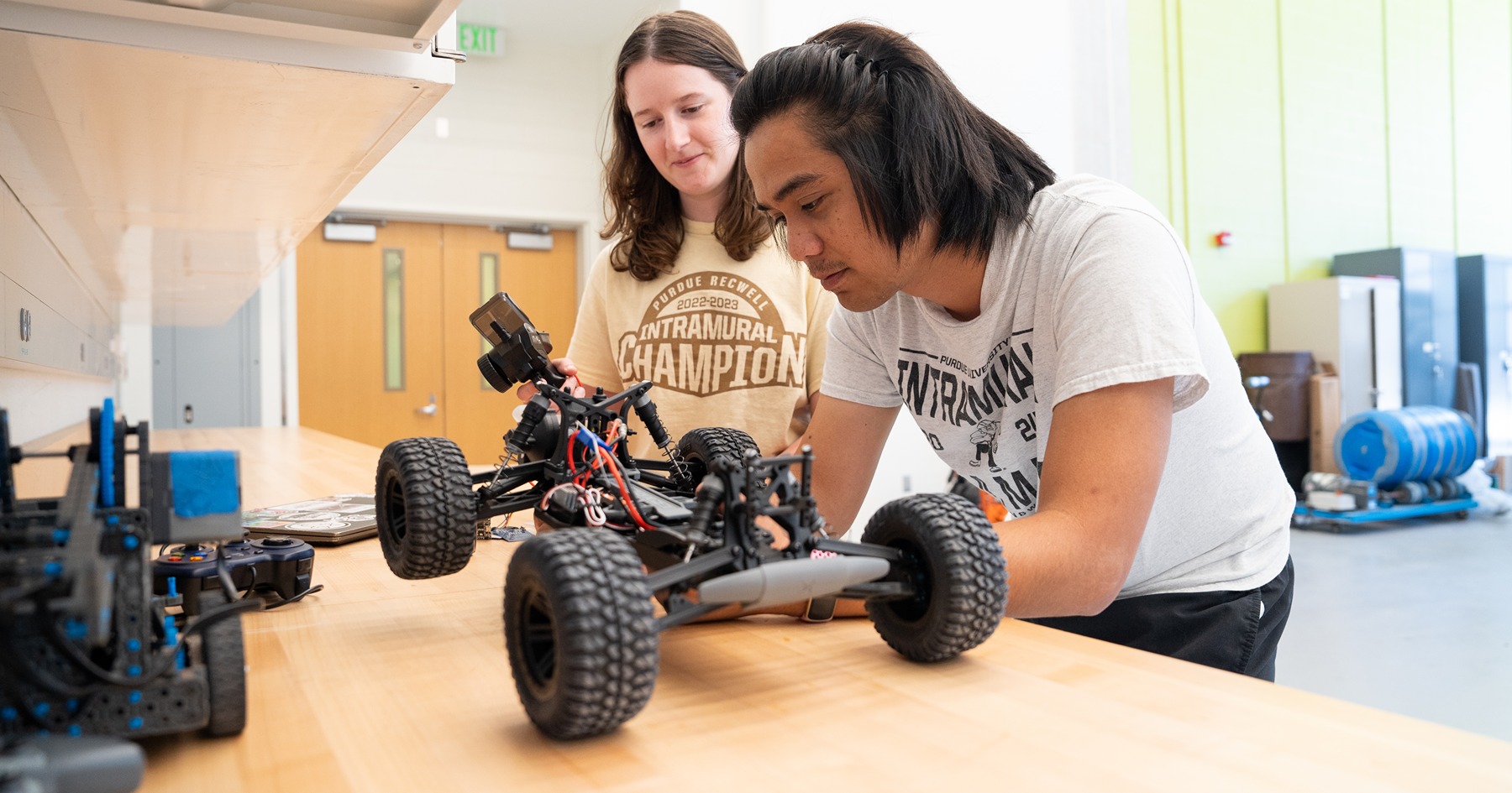 two students lean over a counter as the tinker on a remote controlled car together