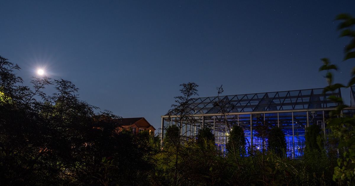 the moon rises over a greenhouse at the Horticulture Building