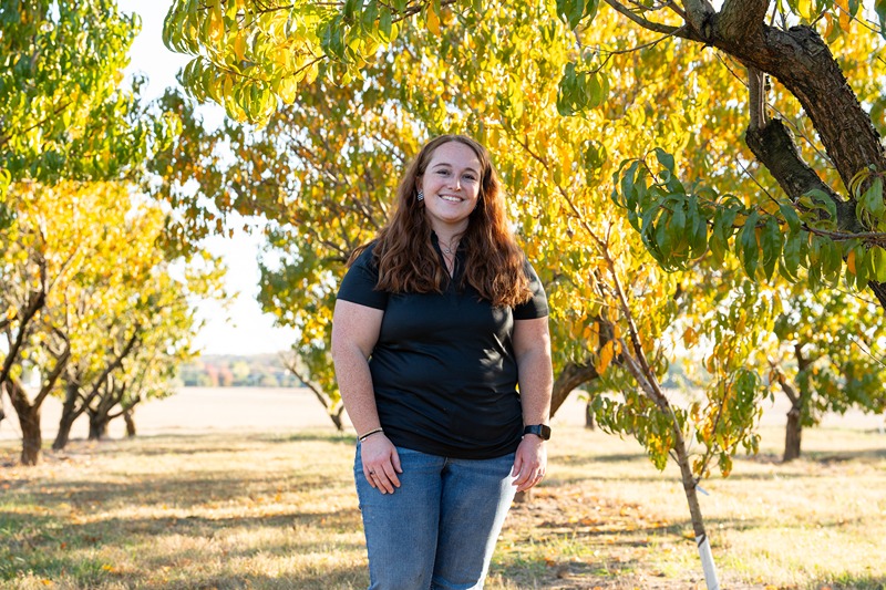 Mariah Schaeper poses in the apple orchard at Wea Creek.