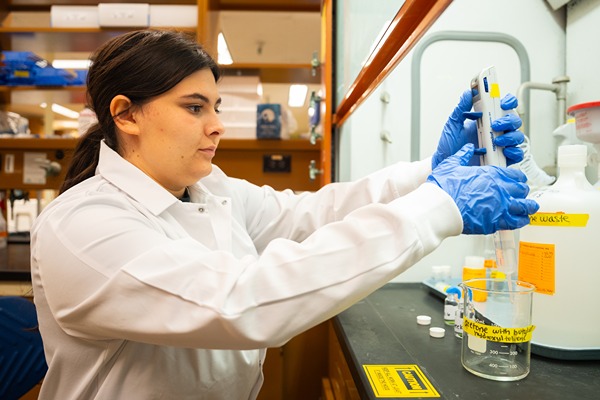 Mary-Margaret uses a micropipette and a beaker in her lab's fume hood