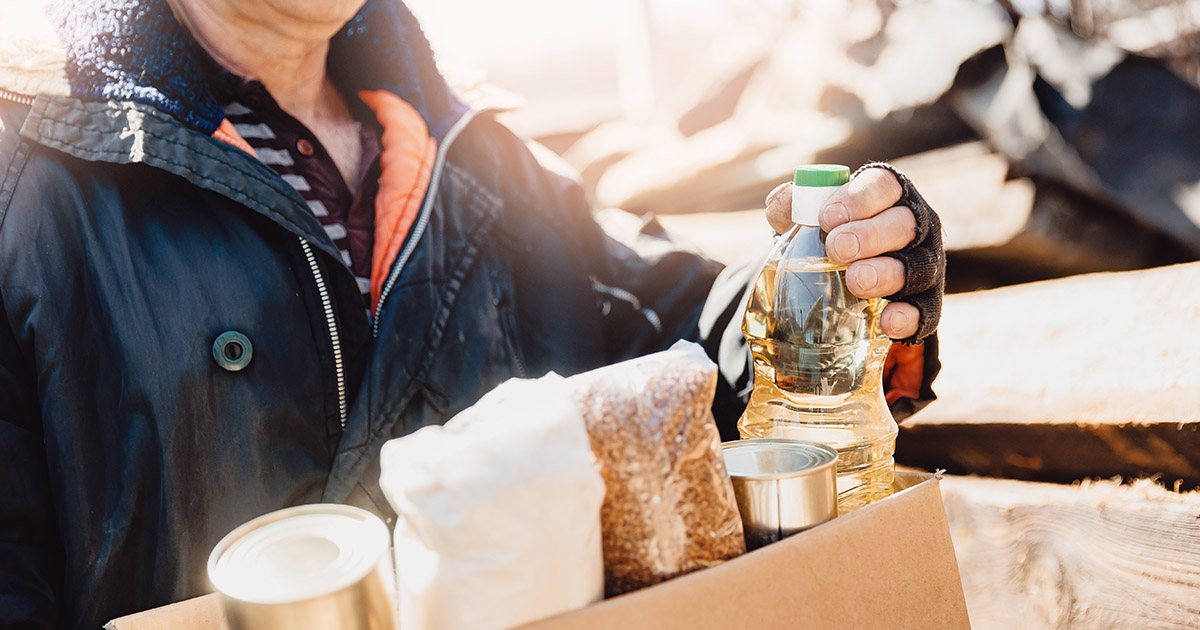 Person holding box of food standing outside.